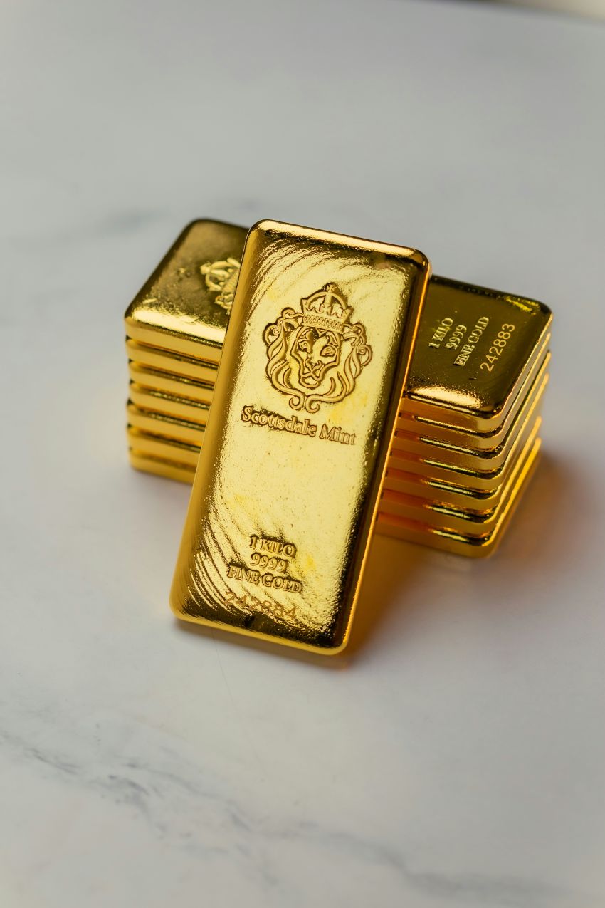estapelte Goldbarren aus Feingold mit Prägung und Seriennummer liegen auf einer hellen Oberfläche.